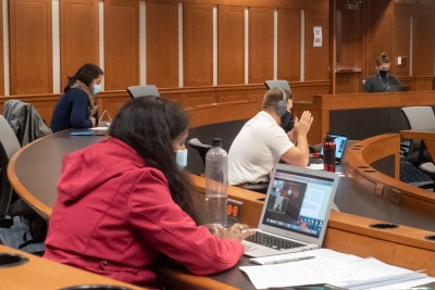 Students wearing masks sit at their laptops in a socially distanced classroom