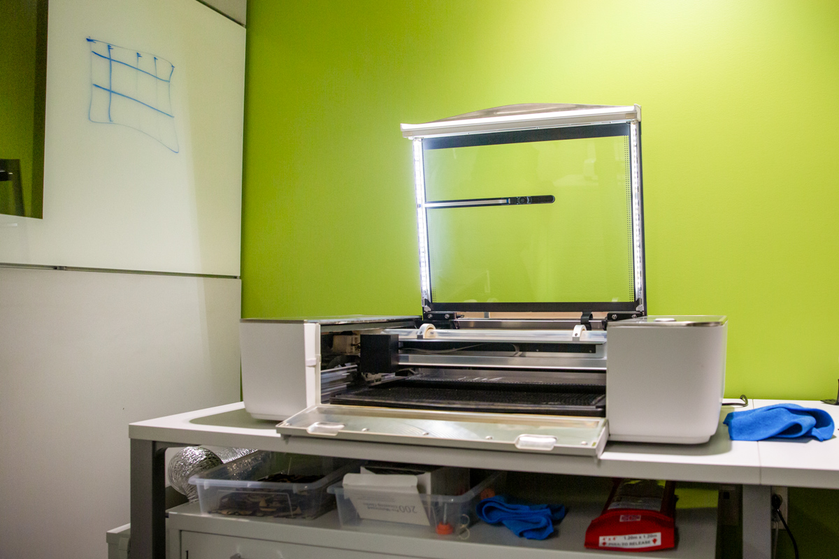 The Glowforge Plus, open with its lights illuminating the interior