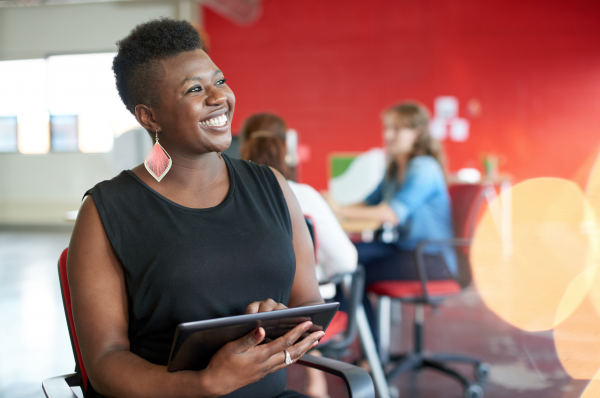 Female instructor holding an iPad smiles as she speaks with another off screen figure