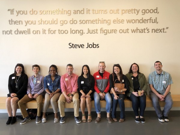 Group visiting Apple HQ with Digital Flagship. 8 participants seated beneath Steve Jobs quote.