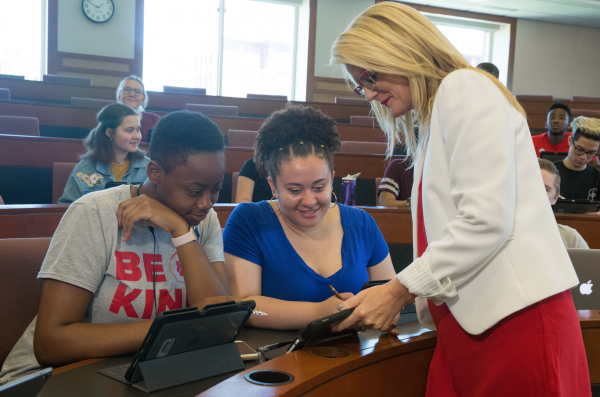 Instructor holding iPad speaks with two students
