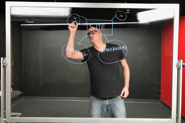 City and Urban Planning Professor Kyle Ezell draws a diagram on a lightboard as he films a video lecture for his class on land development planning.