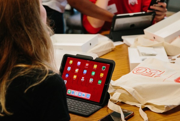 This image shows a student sitting in front of an iPad displaying the 2018 winning background image.