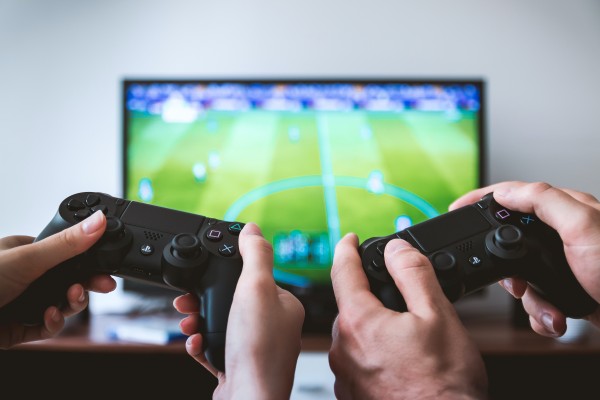 Two students play a Playstation game on the TV in their dorm room