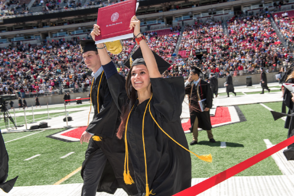 Ohio State graduate holding diploma overhead.