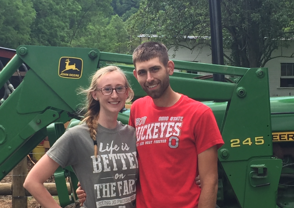 Shana Angel and friend in front of a John Deere tractor.