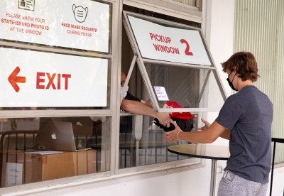 A Digital Flagship staff member passes a backpack containing an iPad kit out of a window to an Ohio State student.